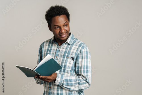 Black unshaven man in plaid shirt posing with exercise book