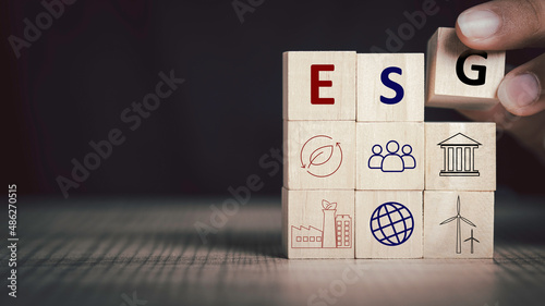 Environmental, social and governance (ESG) concept. Sustainable corporation development. Hand hold wooden cube with abbreviation ESG standing with other ESG icons on black background and Copy space.