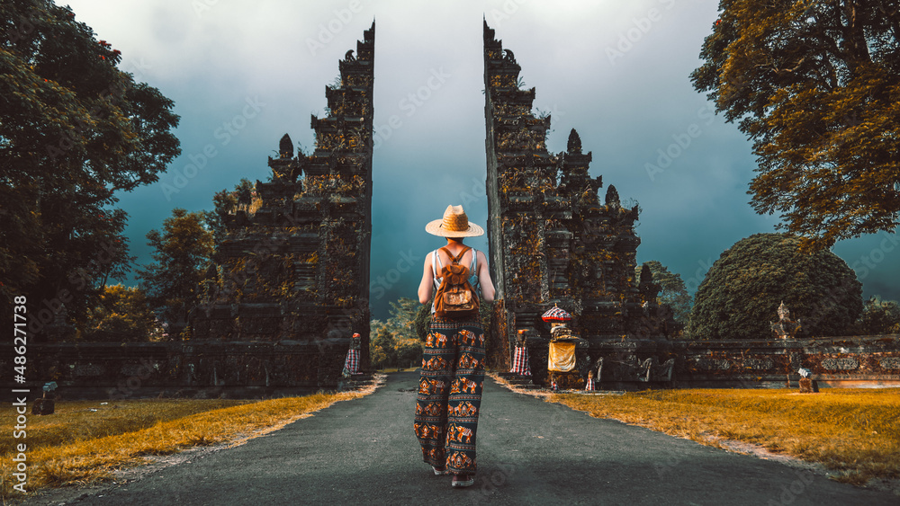 Tourist woman with backpack at vacation walking through the Hindu temple in  Bali in Indonesia Stock Photo | Adobe Stock