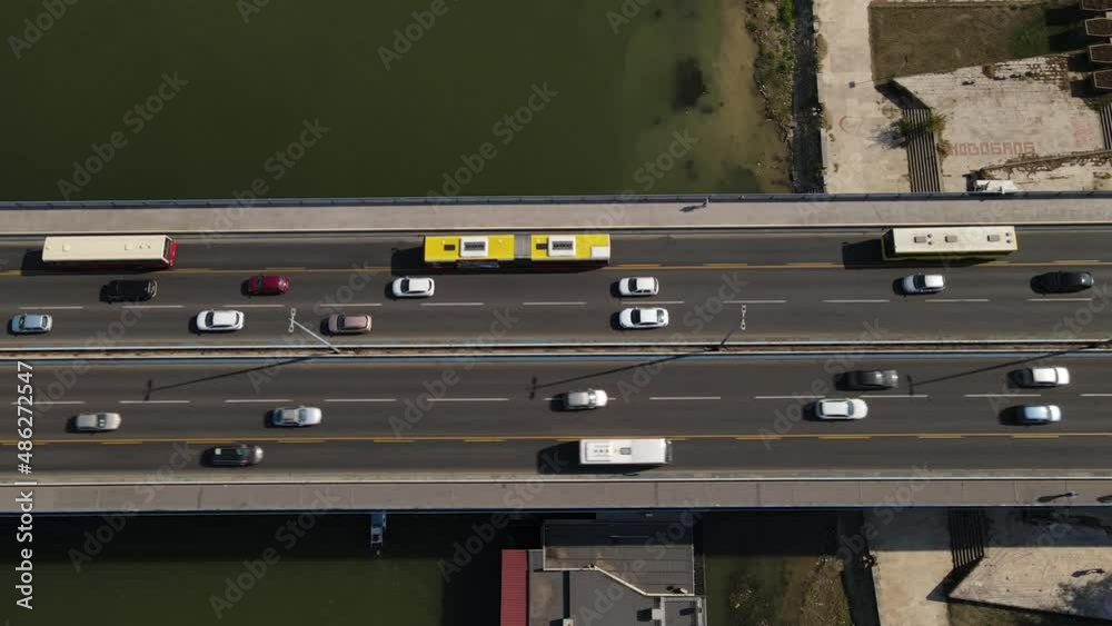 Birds Eye Aerial View of Busy Traffic on Highway Bridge Above River, Buses, Cars on Sunny Day in Modern City Birds Eye Aerial View of Busy Traffic on Highway Bridge Above River, Buses, Cars on Sunny Day in Modern City