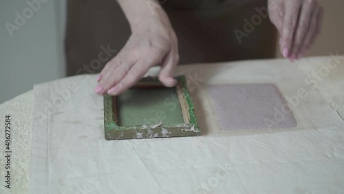 A woman holding a frame for making paper sheets from recycled paper. Selective focus. Household hobby, paper recycling. The concept of zero waste, recycling, ecology