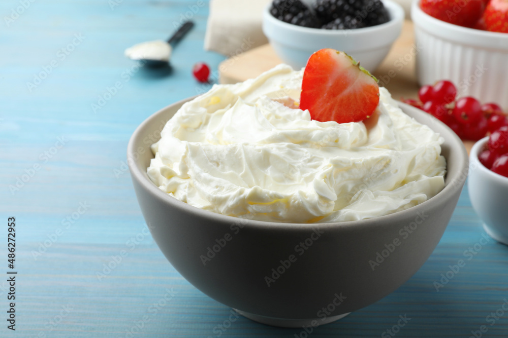 Tasty cream cheese and fresh berries on light blue wooden table Tasty cream cheese and fresh berries on light blue wooden table