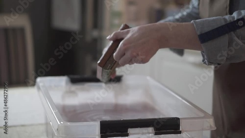 A woman holding a frame for making paper sheets from recycled paper. Selective focus. Household hobby, paper recycling. The concept of zero waste, recycling, ecology