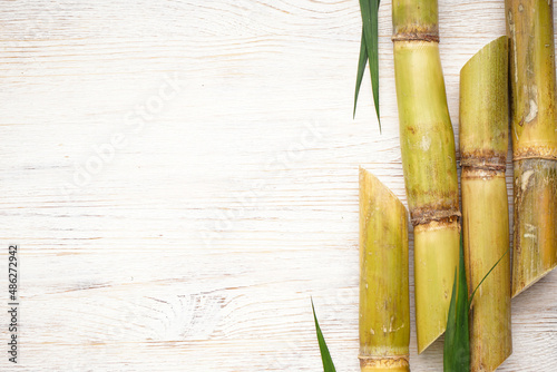 Sugarcane and green leaf close up on rustic white table  space for text. Flat lay.