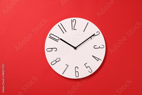 Modern clock on red background, top view