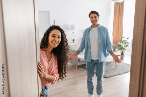 Papier peint Happy young couple inviting people to enter their apartment
