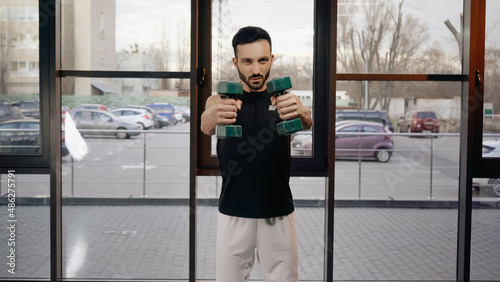 Muscular sportsman training with dumbbells in sports center Free Download Muscular sportsman training with dumbbells in sports center - GFXLoad
