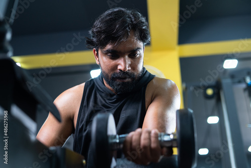 young man doing forearms workout using dumbbells at gym - cocept of fitness training, bodybuilding and healthy lifestyle. photo