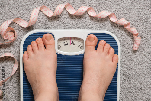 Women's feet on floor scales, top view. 30 or 40 kilograms on a scale, the idea of anorexia and eating disorders