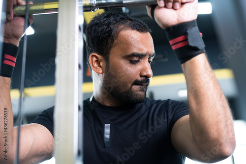 Young indian bodybuilder doing biceps workout at gym - concept of body fitness, muscle building exercise and determination. © WESTOCK