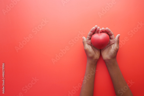  man hand in protective gloves holding red heart on blue 