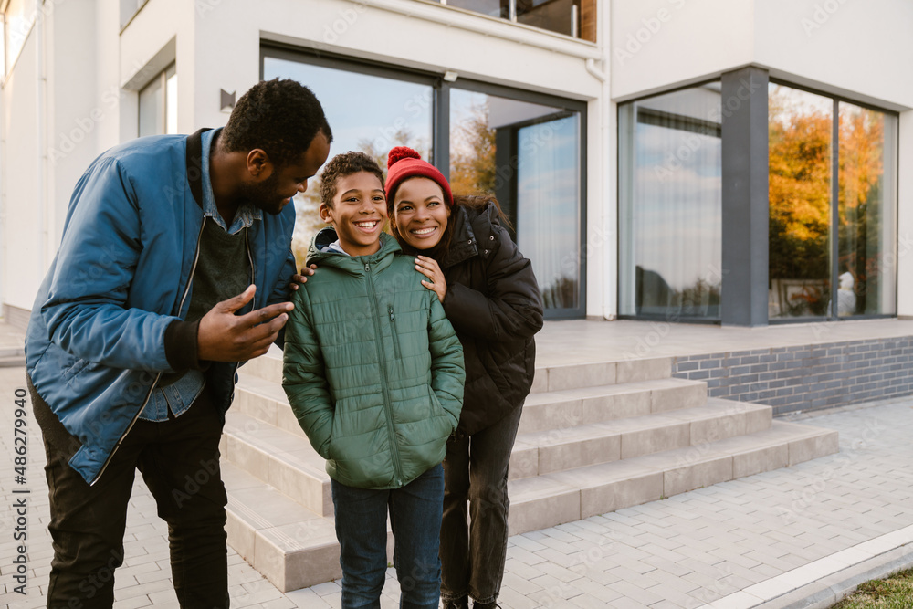 Black family smiling and talking while standing by house