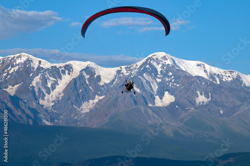paraglider with a motor with two pilots on the background of Mount Aktru in the Altai mountains