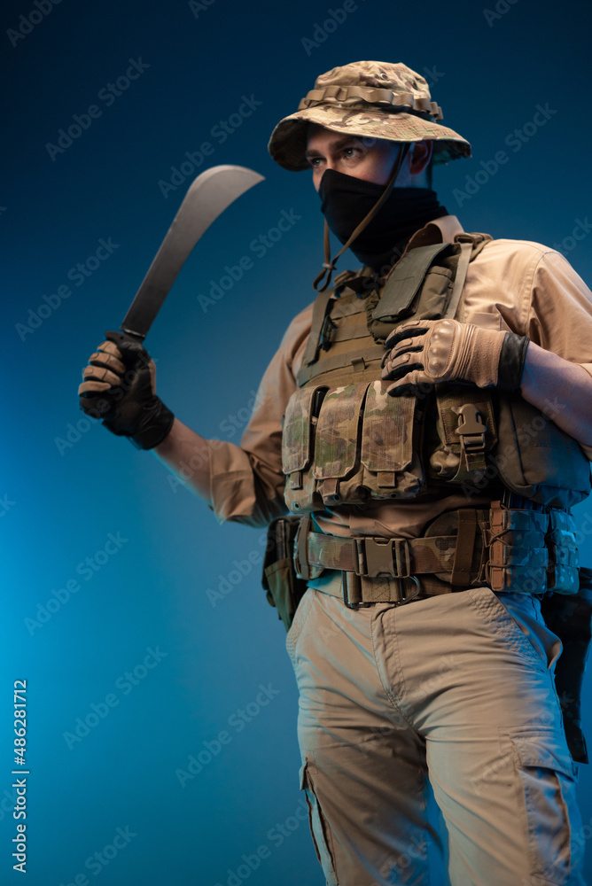 Fototapeta premium an army soldier in military clothes with a machete in his hand