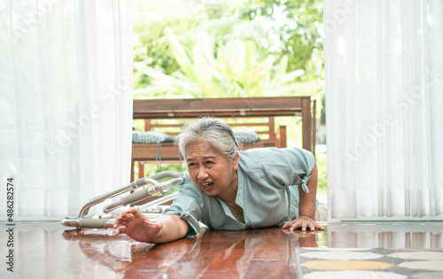 Asian senior woman falling down on lying floor at home after Stumbled at the doorstep and Crying in pain and asking someone for help. Concept of old elderly insurance and health care