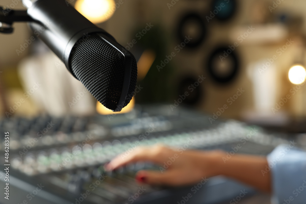 Woman working with professional mixing console in modern radio studio, focus on microphone. Space for text Woman working with professional mixing console in modern radio studio, focus on microphone. Space for text
