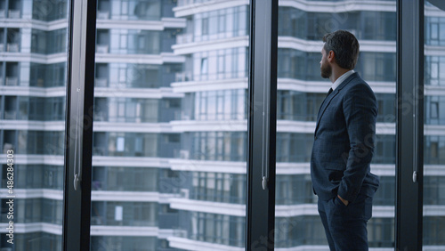 Entrepreneur walking corporate building. Businessman looking window in office.