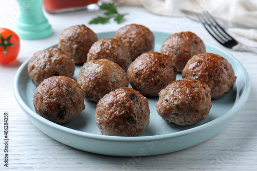 Tasty cooked meatballs served on white wooden table, closeup