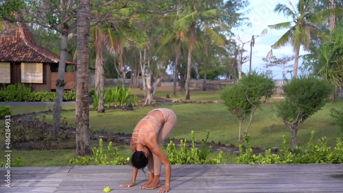 Spiritual yoga practice on the path surrounded by tropical nature, woman doing Salute to the Sun excercise 