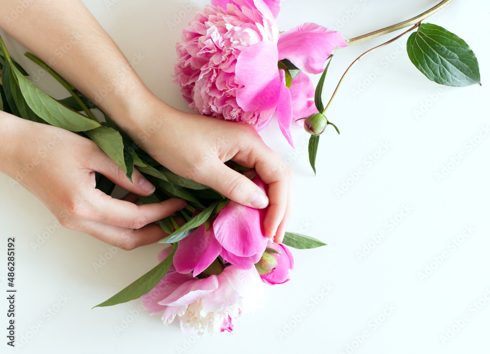 Female hands are holding pink peony flowers. Floral composition. Feminine-styled stock image. Selective focus, blurred background. Spring flowers. Spring background. A place for your text.