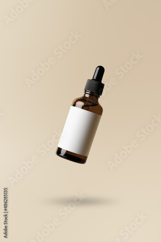 Brown dropper glass bottle flying in antigravity on pastel beige background. Levitation object in the air. Skincare concept. Organic natural cosmetic product. Mockup, minimal style photo