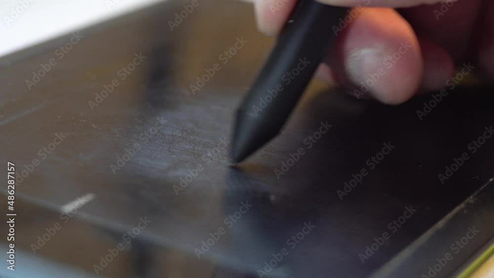 Black electronic pen on a man's hand. Electronic graphics tablet. Drawing on the board. Creative tool. Freelance artist. Creative studio. Designer's work. Illustrator app. Close-up. Black electronic pen on a man's hand. Electronic graphics tablet. Drawing on the board. Creative tool. Freelance artist. Creative studio. Designer's work. Illustrator app. Close-up.