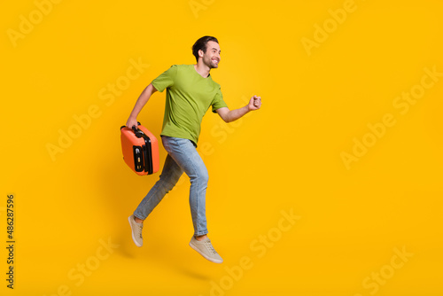 Full body profile side photo of young man runner jumper rush hold bag journey weekend abroad isolated over yellow color background