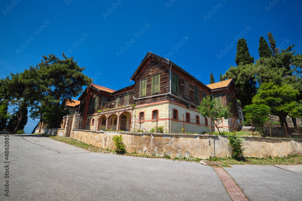 An old house made of stone and wood, trees and pine trees grow nearby. Old orthodox monastery. Travel to Buyukada, Adalar, Prince Islands, Istanbul, Turkey