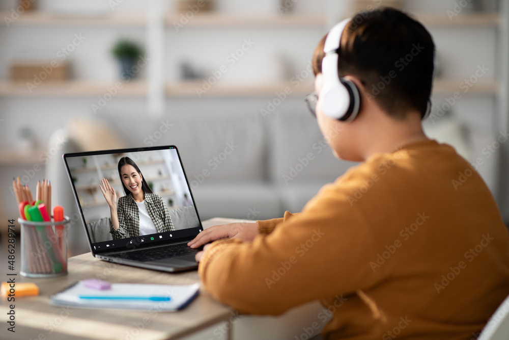 Boy having video conference with teacher, using headset and laptop Boy having video conference with teacher, using headset and laptop