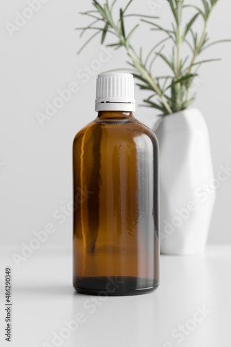 Pharmaceutical bottle mockup with a rosemary on the white table.