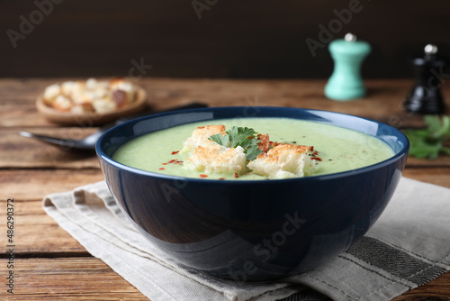 Delicious asparagus soup with croutons served on wooden table