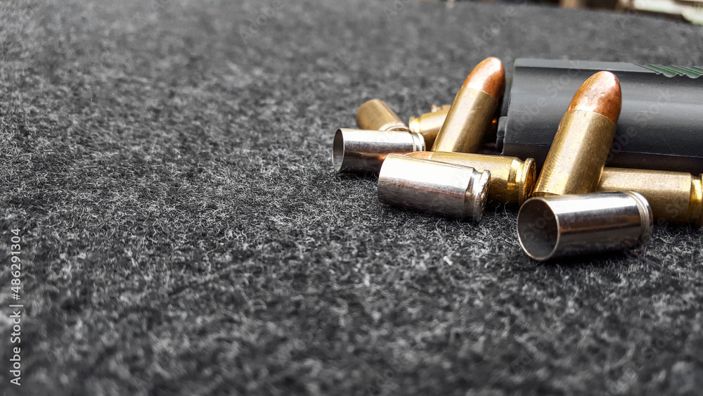 Black artificial handgun and bullets on dark gray fabric. Concept for security of social, personal and shooting sport equipments Black artificial handgun and bullets on dark gray fabric. Concept for security of social, personal and shooting sport equipments