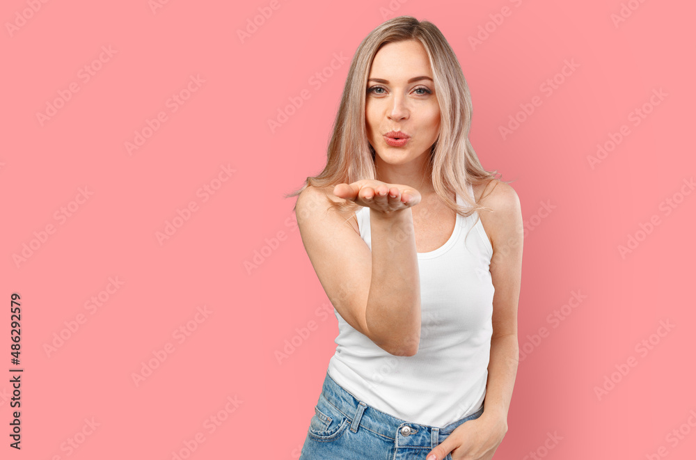 Pretty blonde woman blows kiss into camera isolated on color background. Pretty blonde woman blows kiss into camera isolated on color background.