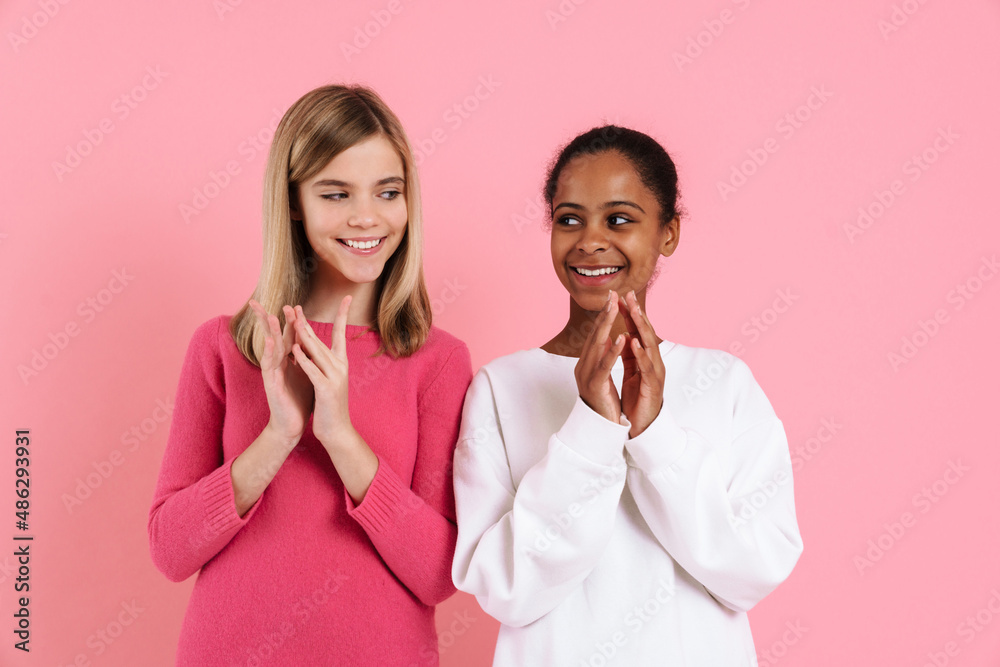 Multiracial two girls smiling while holding hands together Multiracial two girls smiling while holding hands together