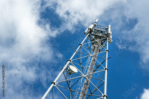 Bottom perspective pov of modern metal steel mobile 5g network wireless telecom tower against clear blue sky background on bright day. Microwave signal broadband equipment base line station mast