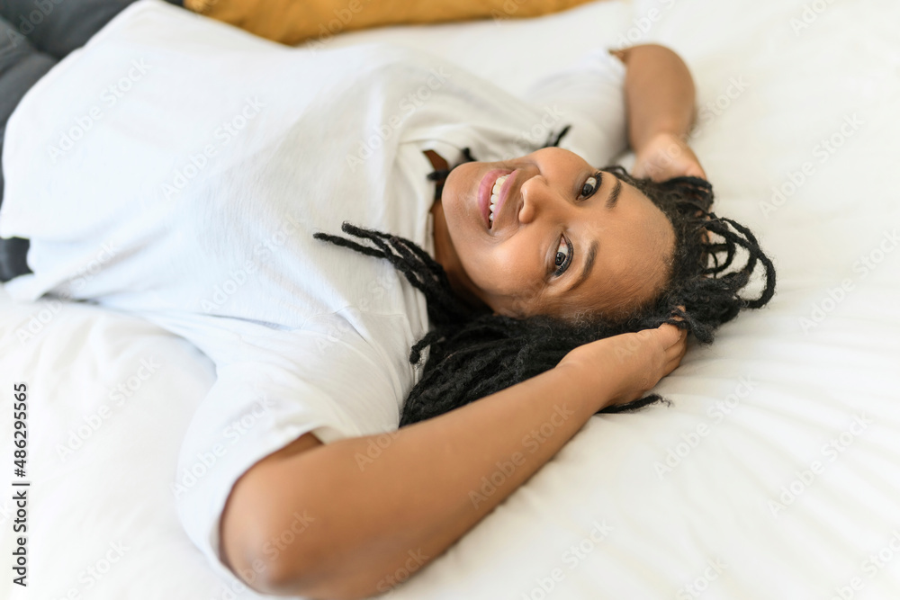 Portrait of an african woman lay on a white bed