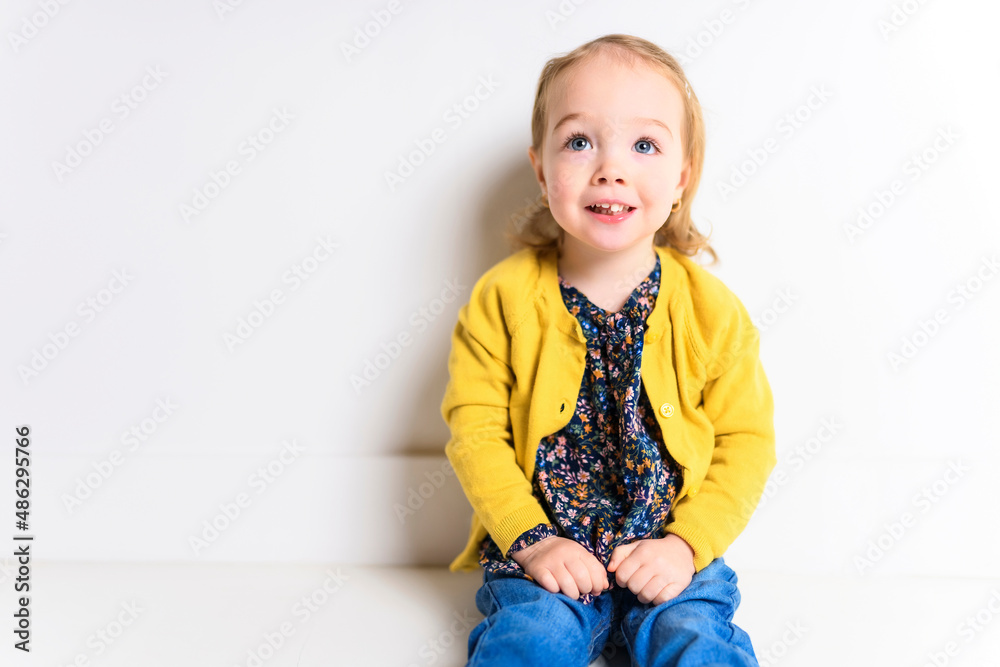 Cute playful baby girl sitting on the floor of a white background Cute playful baby girl sitting on the floor of a white background