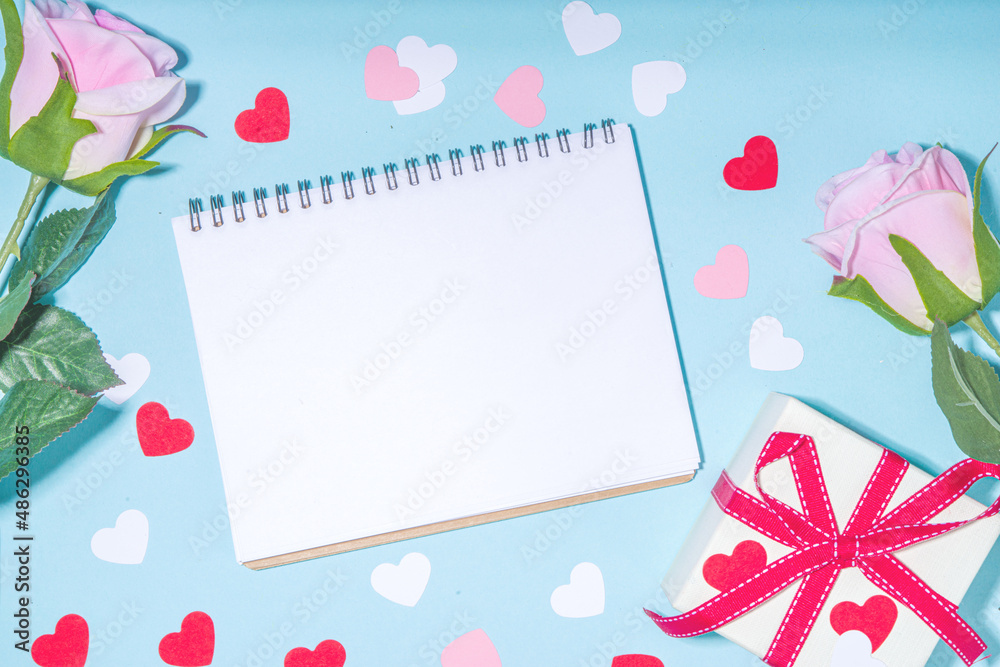 Valentine day simple greeting card flatlay. Valentines holiday background with red, pink, white hearts, pink roses, gift box, top view copy space on light blue background