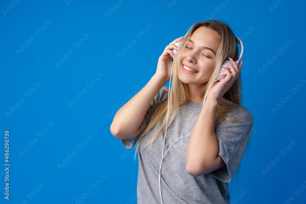 Happy young woman with headphones on a blue background Happy young woman with headphones on a blue background