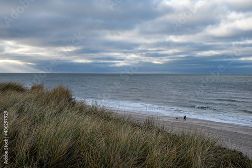 Ein Paar mit Hund geht im Winter am Strand von Kampen Insel Sylt spazieren