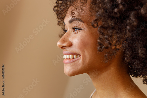 Multiethnic female toothy smiling on beige background