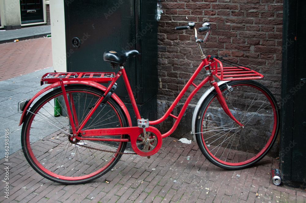 A red bicycle parked on a street in the center of Amsterdam, Netherlands.