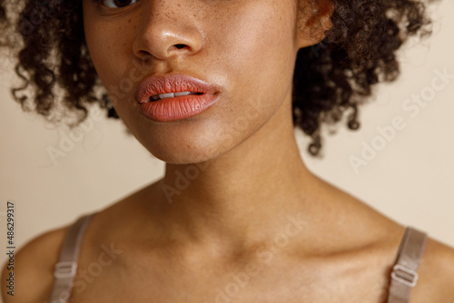 Female model with natural makeup posing on beige background