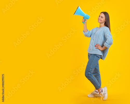 Happy woman megaphone. Satisfied woman loudspeaker. Woman with megaphone in full growth. Young age girl advertises something concept. Loudspeaker is marketing metaphor. Place for ads on yellow