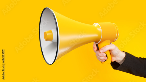 Loudspeaker close-up. Megaphone in woman's hand. Yellow speaker. Megaphone as metaphor for propaganda and marketing. Loudspeaker for your advertising banner yellow megaphone close-up