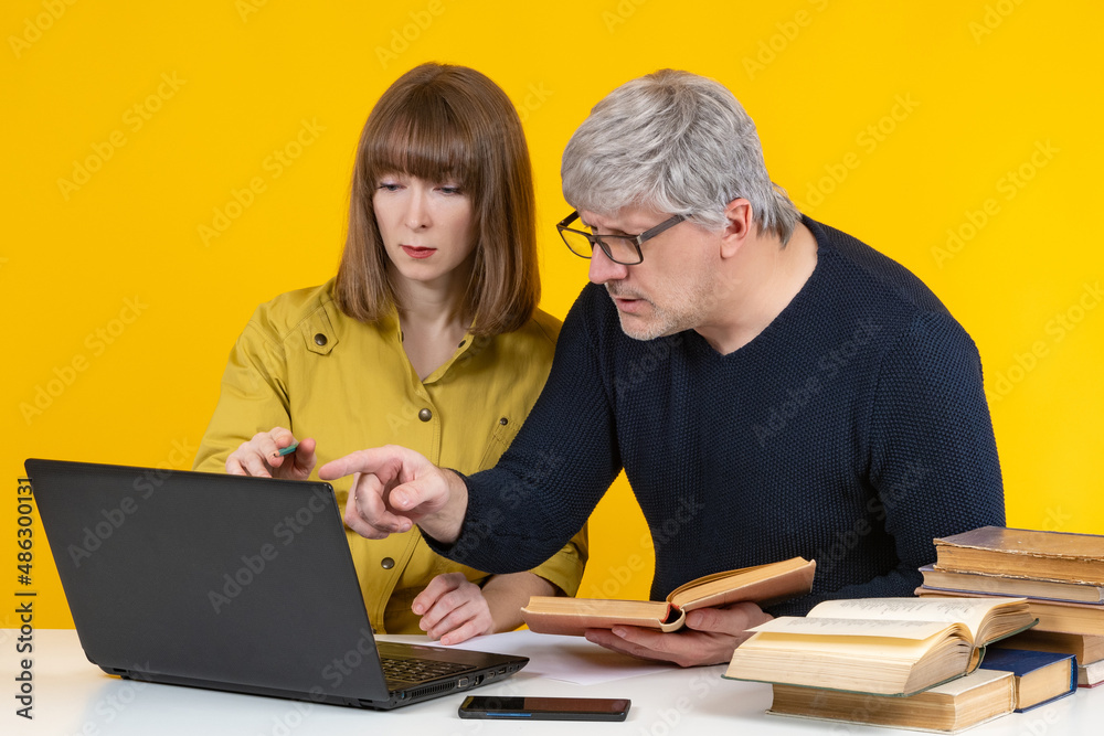 Student and tutor on yellow. Man tutor teaches girl. Guy and girl are sitting in front of laptop. Gray-haired teacher is engaged in tutoring. Teacher helps student prepare for exam. Teaching career Student and tutor on yellow. Man tutor teaches girl. Guy and girl are sitting in front of laptop. Gray-haired teacher is engaged in tutoring. Teacher helps student prepare for exam. Teaching career