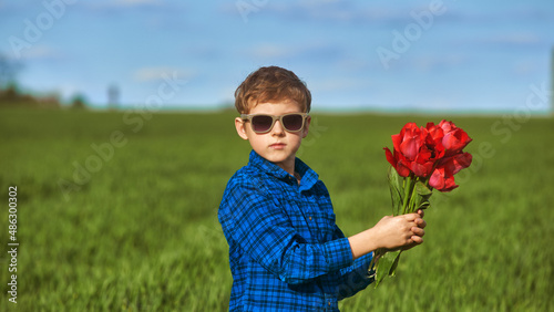 Portrait of a boy with a bouquet of red tulips outdoors
