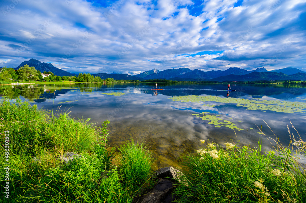 Stand up paddling at Lake Hopfensee near Fuessen - View of Allgaeu Alps, Bavaria, Germany - paradise travel destination