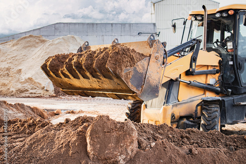 The excavator loader works with a bucket for transporting sand at a construction site. Professional construction equipment for earthworks.