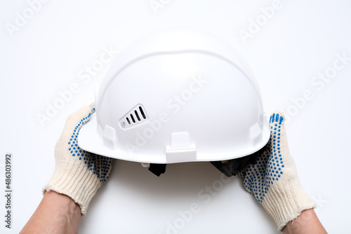 Hands of a worker, builder holding a white protective hard hat, safety helmet against white background